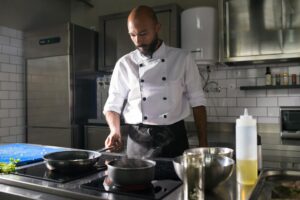 The Rise of AI Recipe Apps Among Professional Chefs Professional chef working in modern commercial kitchen with stainless steel equipment and organized workstation