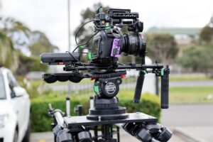 Professional video camera on tripod in filming setup with lighting equipment