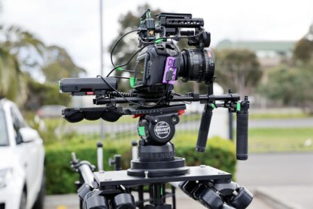 Professional video camera on tripod in filming setup with lighting equipment