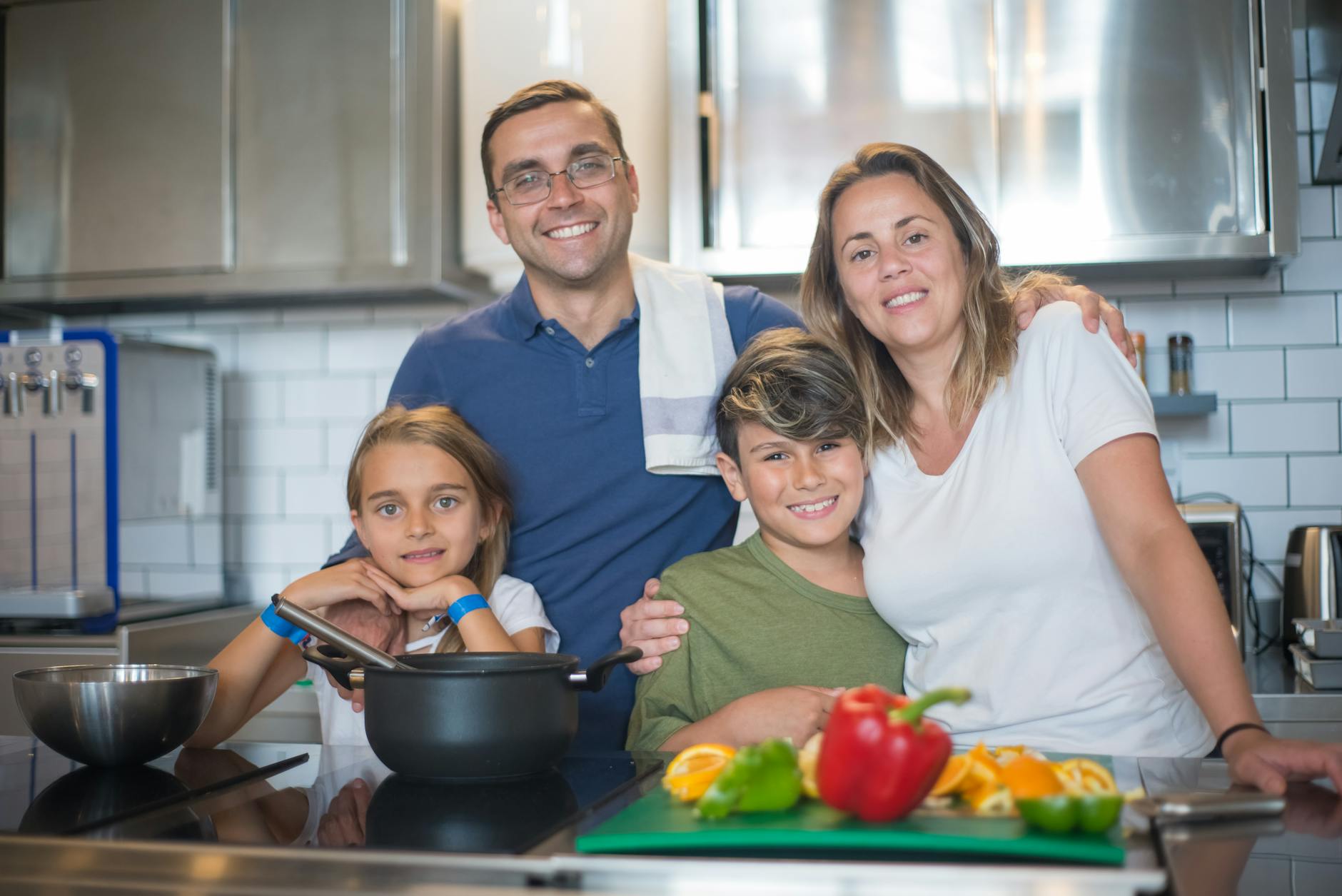 Parent cooking in modern kitchen while child plays nearby, representing multitasking scenarios where voice shopping thrives
