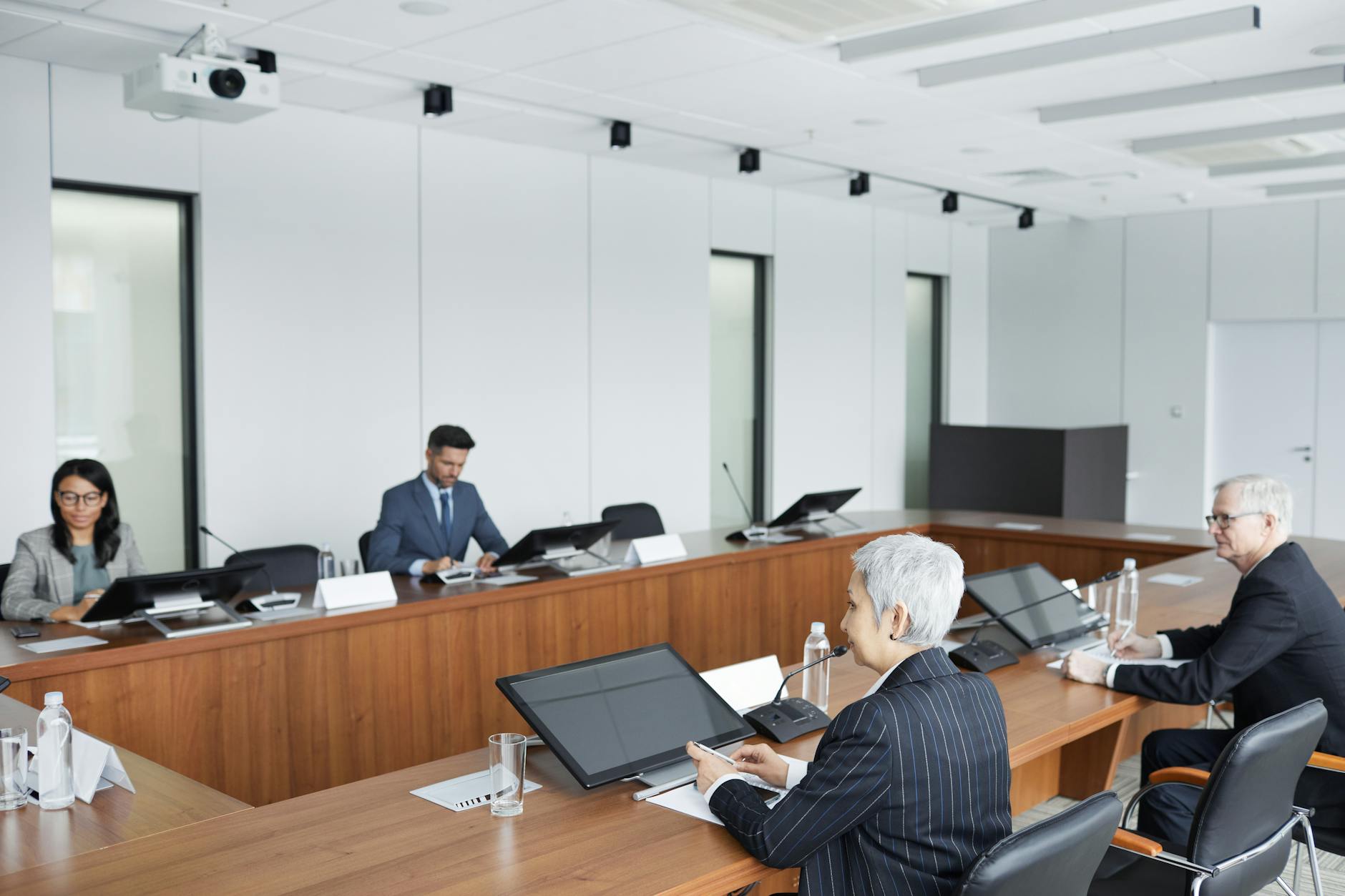 Professional business meeting in modern boardroom with people discussing documents and presentations