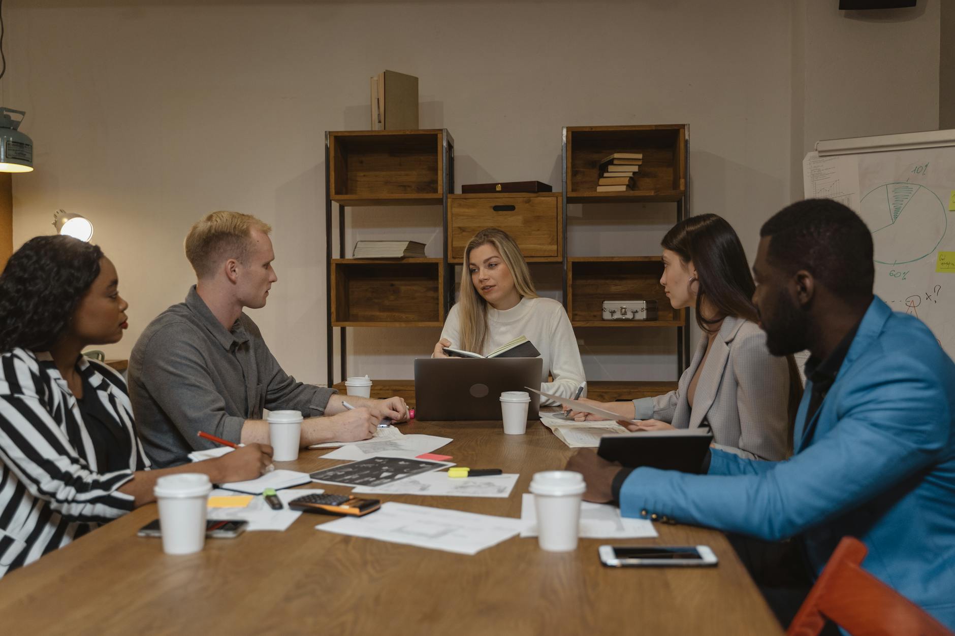 Business team collaborating around conference table with laptops and documents in modern office setting
