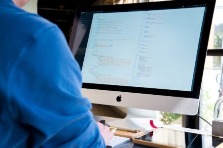 Linear’s Project Management Tool Is Stealing Jira’s Developer Loyalists Developer working at a computer desk with multiple monitors showing code and project management tools