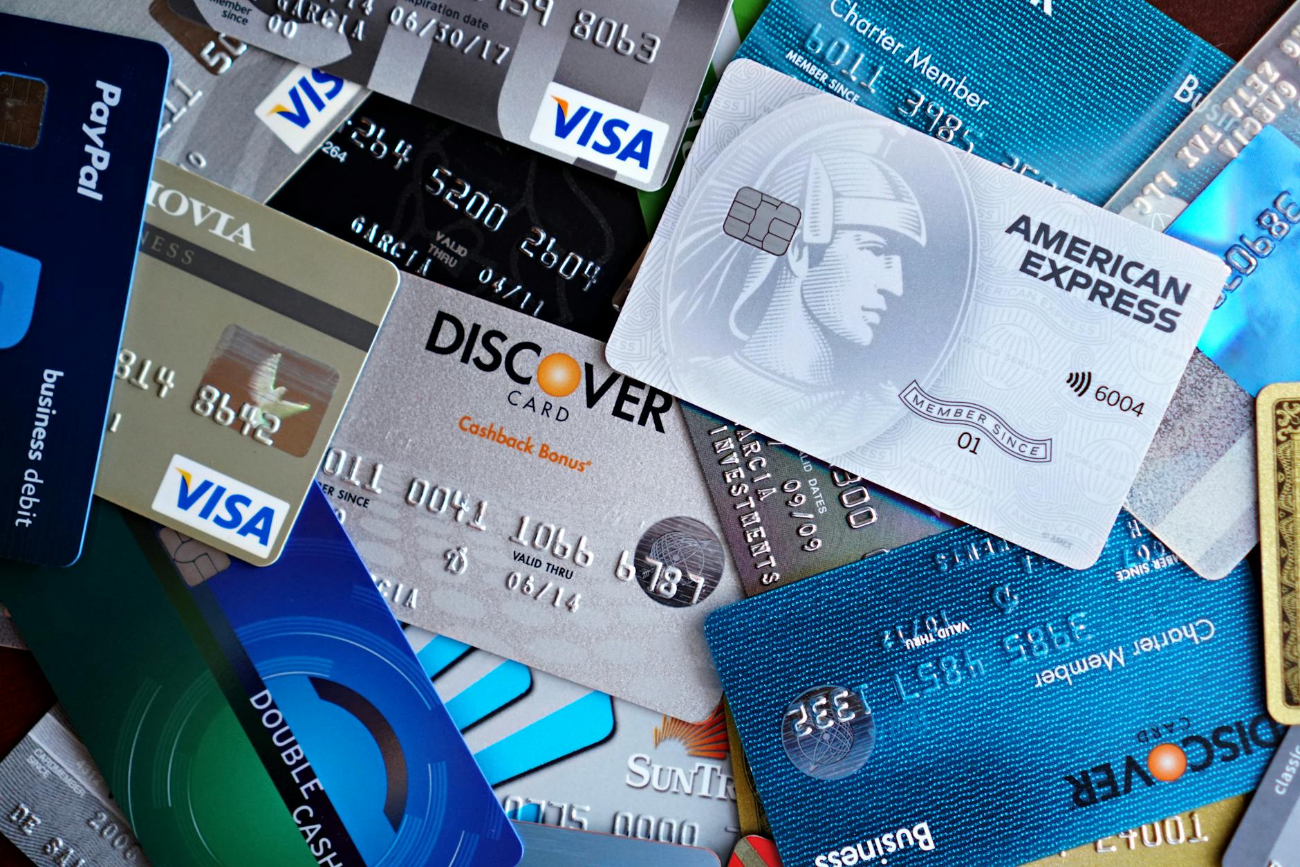 Hand holding credit card next to laptop for online payment transaction