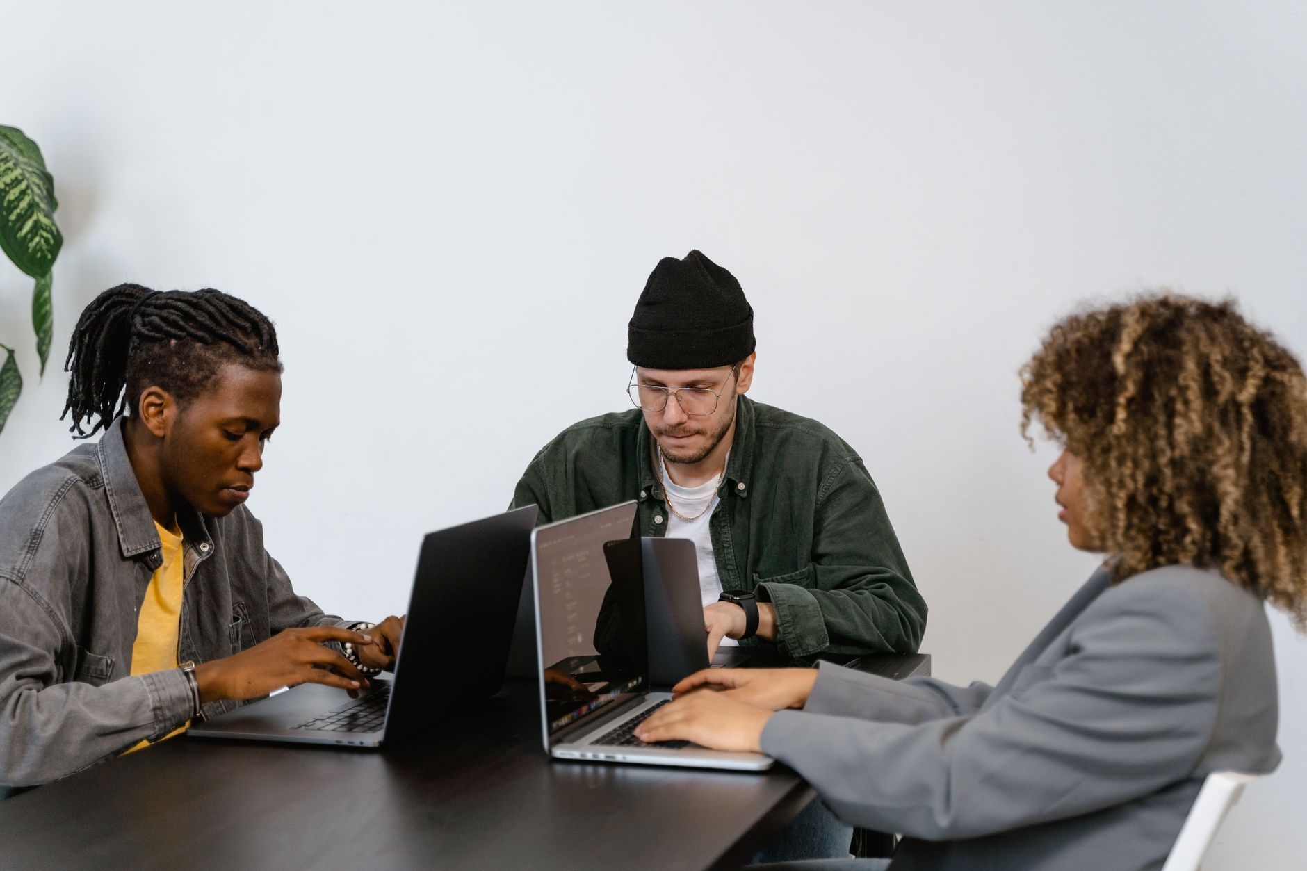 Small startup team collaborating around a table with laptops and design mockups