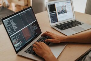 A developer writing code on a laptop in a modern office environment