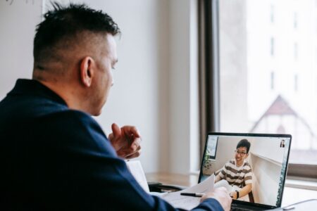 Professional on a video call taking meeting notes on a laptop