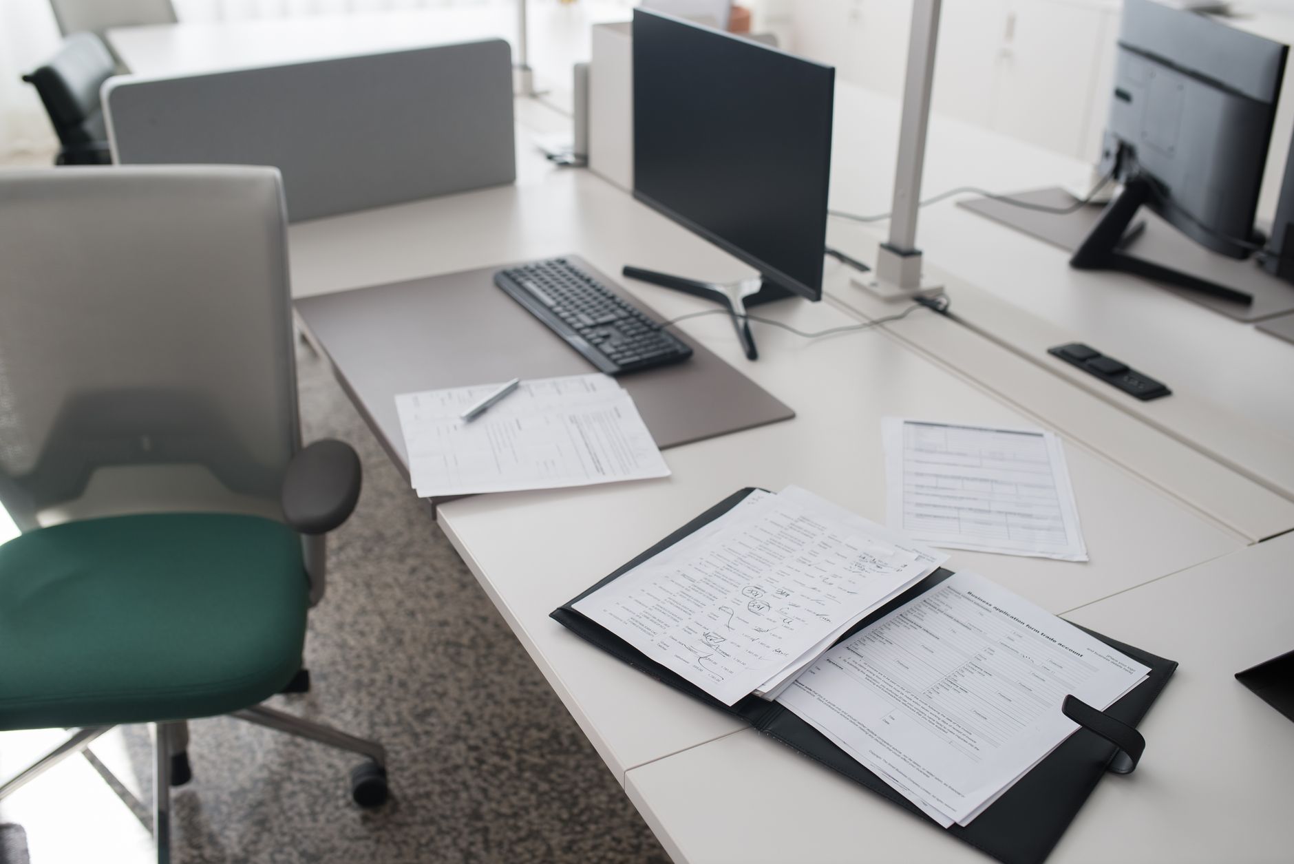 A recruiter reviewing candidate materials at a desk with a computer monitor showing interview notes