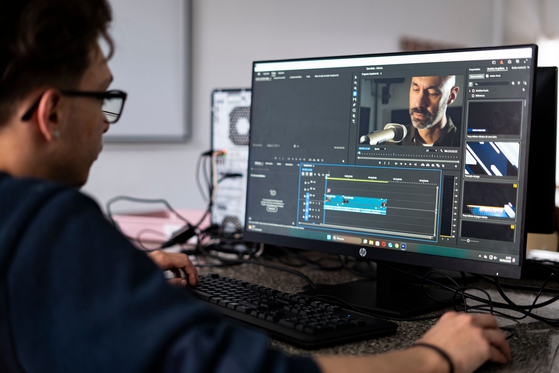 A person editing video footage on a desktop computer with a timeline interface visible on screen