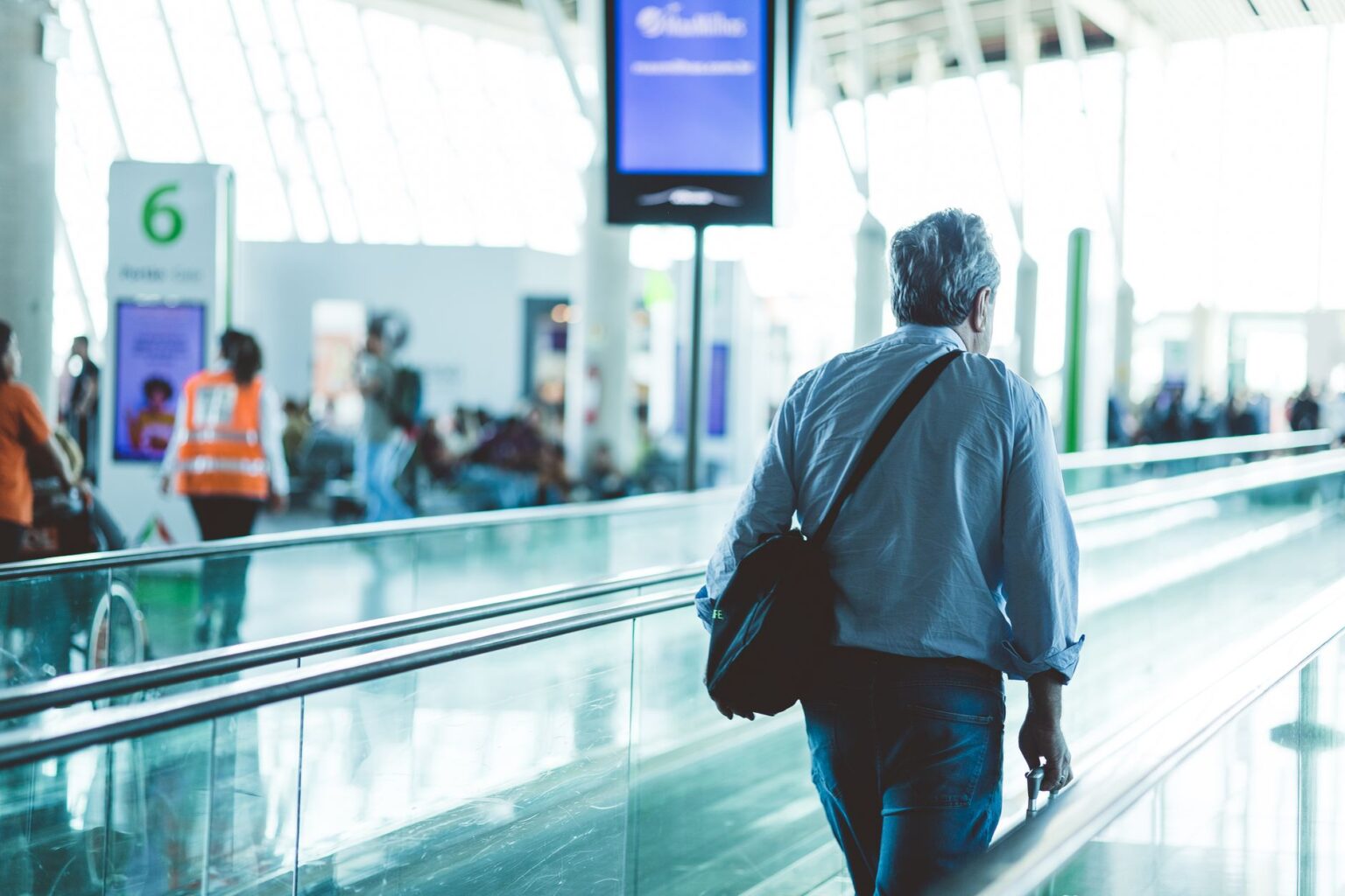 Business traveler at airport terminal checking phone during corporate trip