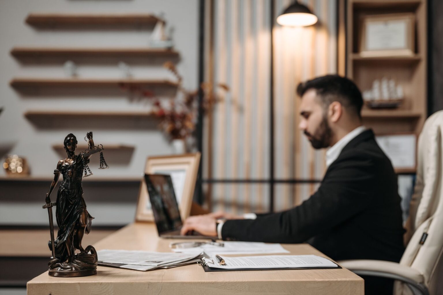 Attorney working at a desk with documents and a laptop in a law office setting