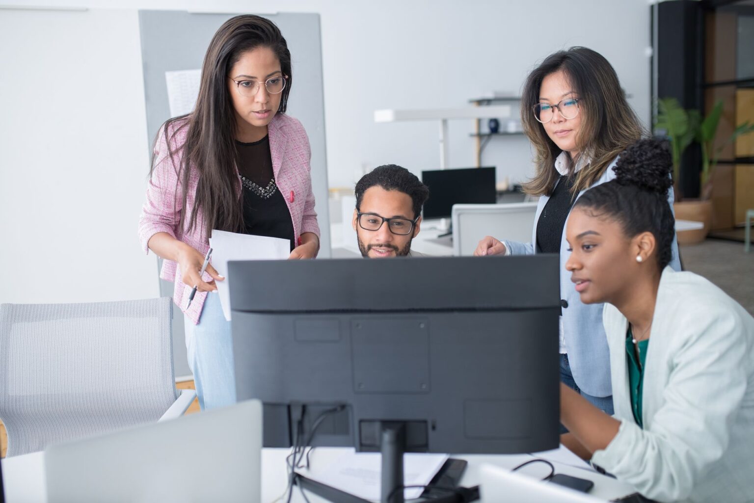 Enterprise team collaborating around screens in a modern office environment