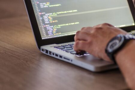 Developer working on a laptop with code on screen, representing AI coding tools