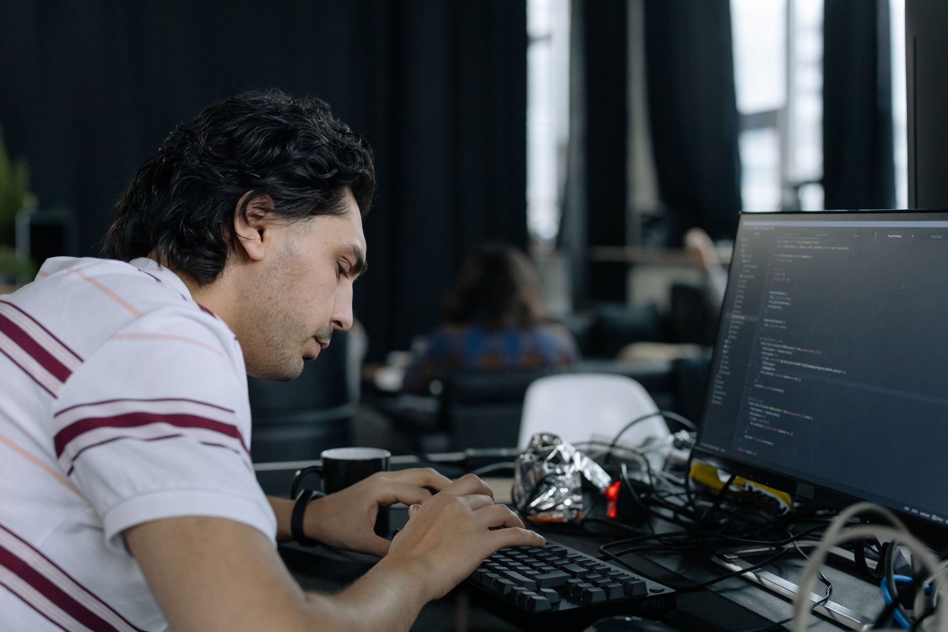 Software developer writing code on a laptop in a modern office environment
