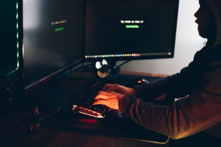 A developer reviewing fraud detection data on multiple screens in a tech office environment