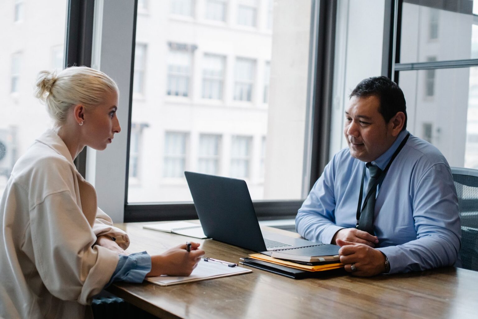 Two professionals conducting a job interview across a desk in a modern office