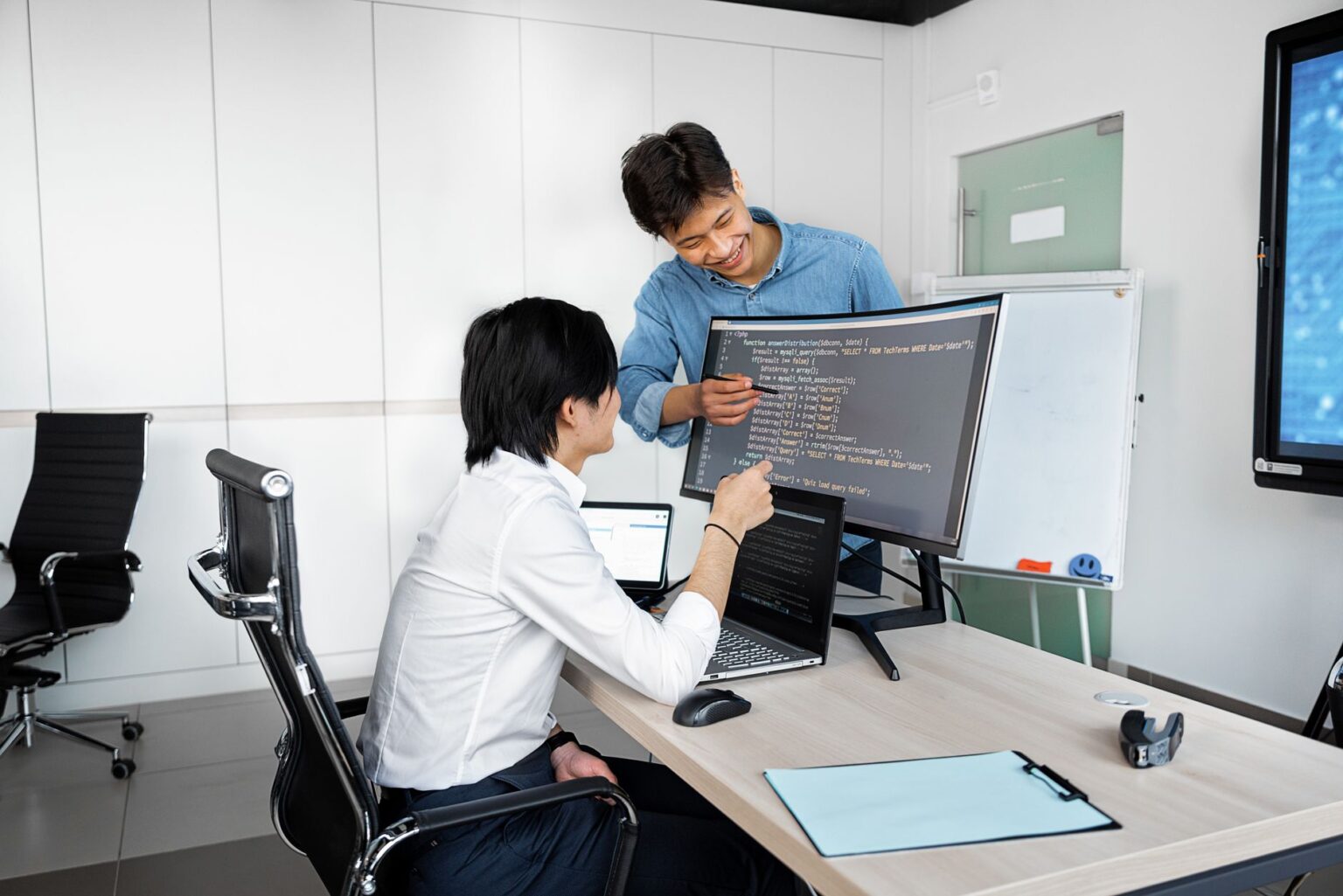 Two developers working together at a computer screen reviewing code