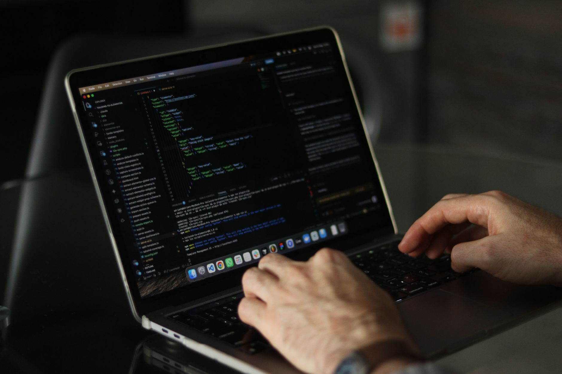 Developer writing code on a laptop screen in a modern workspace