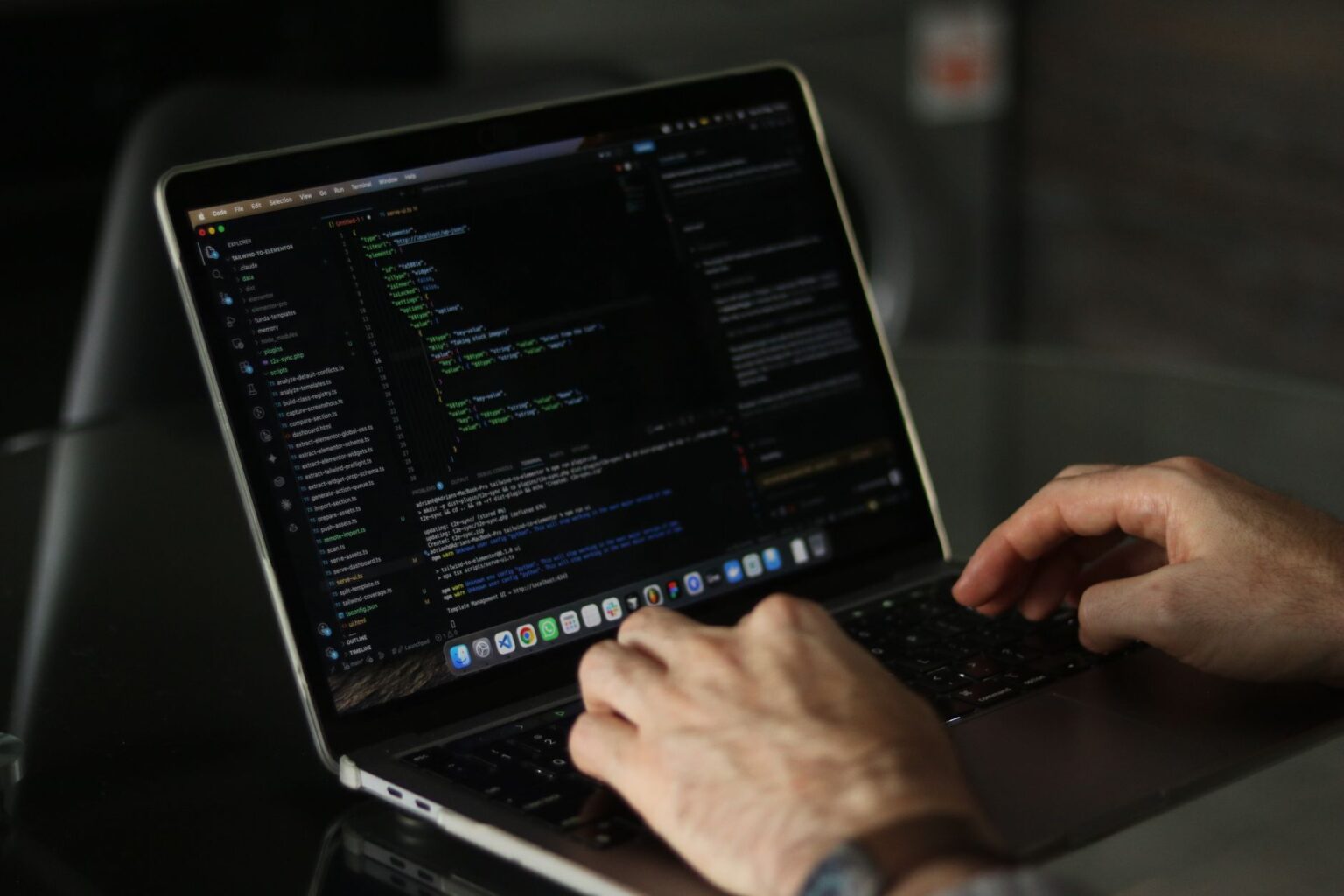 Developer writing code on a laptop in a modern workspace
