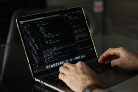 Developer writing code on a laptop in a modern workspace