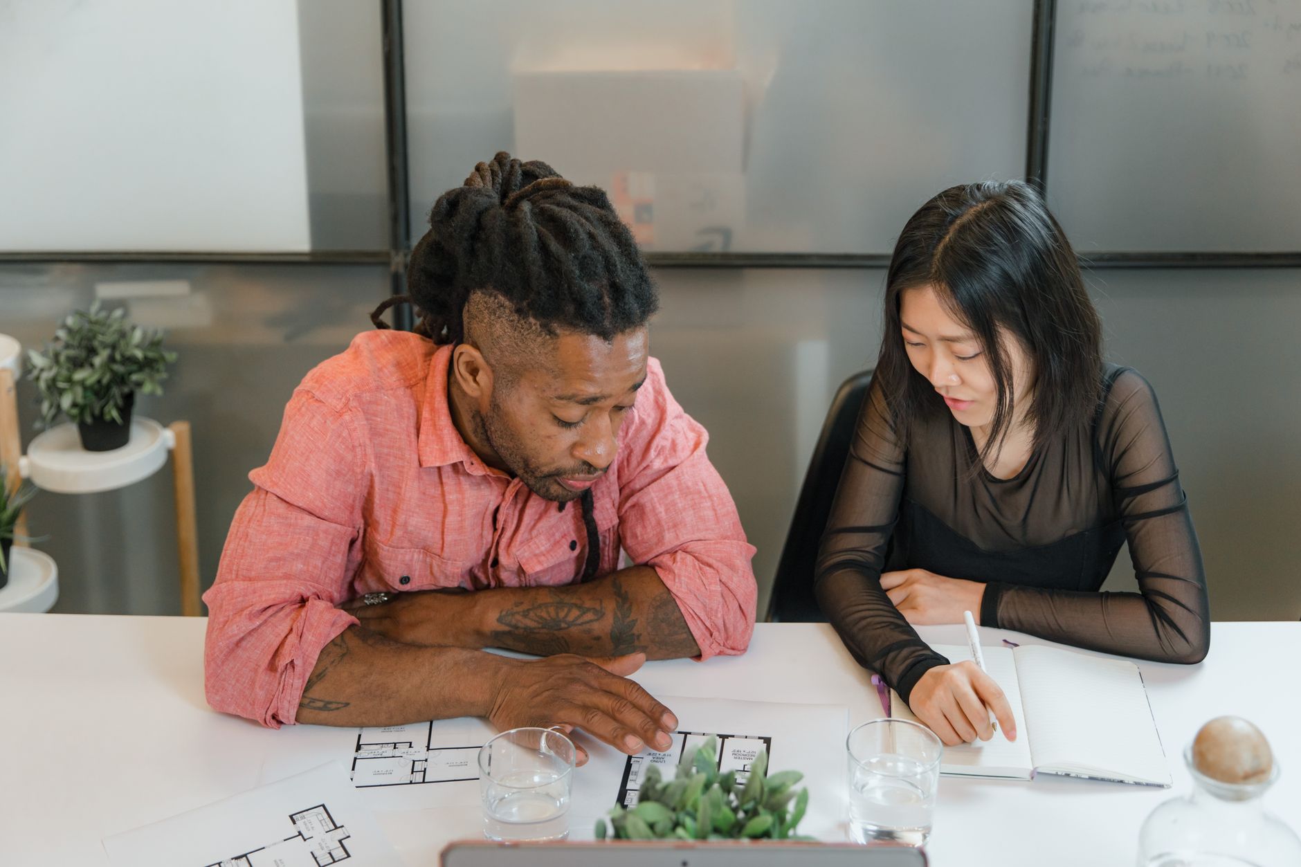 Two colleagues reviewing a digital workflow dashboard on a monitor