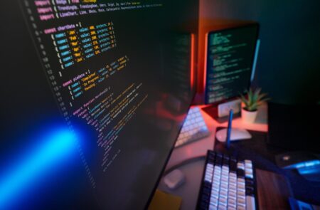 Developer working at a computer with multiple screens showing code and UI components