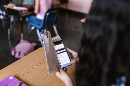 Speak’s Language App Is Quietly Cornering Duolingo’s Power Learner Base Person using a smartphone app for language learning at a desk