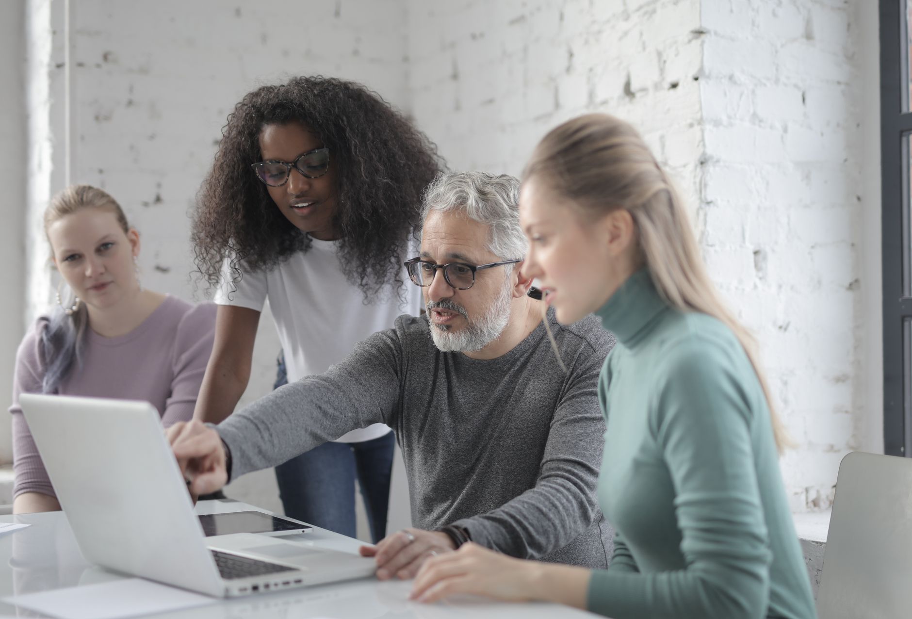 Professionals collaborating around laptops in a modern office meeting room